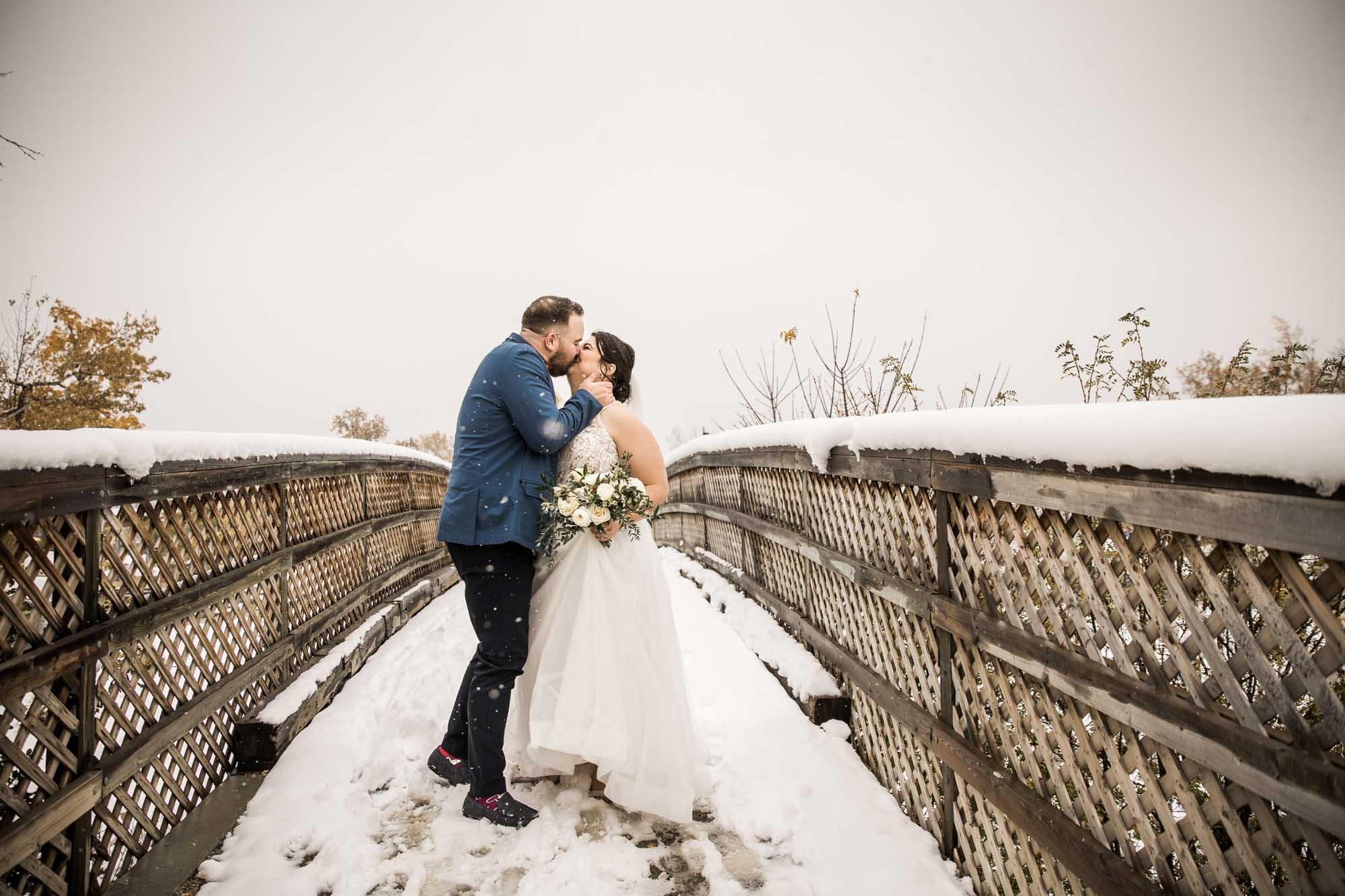 Calgary wedding photographer, bride in her dress with her bridal flowers and groom on their wedding day at St Patrick's Island, winter snow and fall leaves